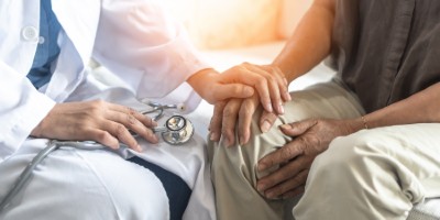 Doctor with his hand on a patient's hand