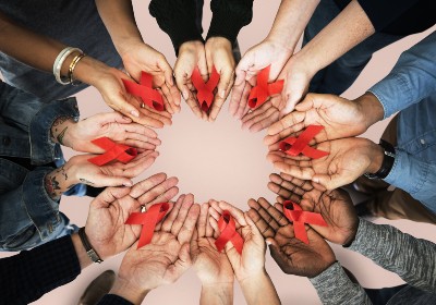 Hands holding red ribbons for HIV