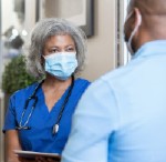 a masked doctor speaks to a patient